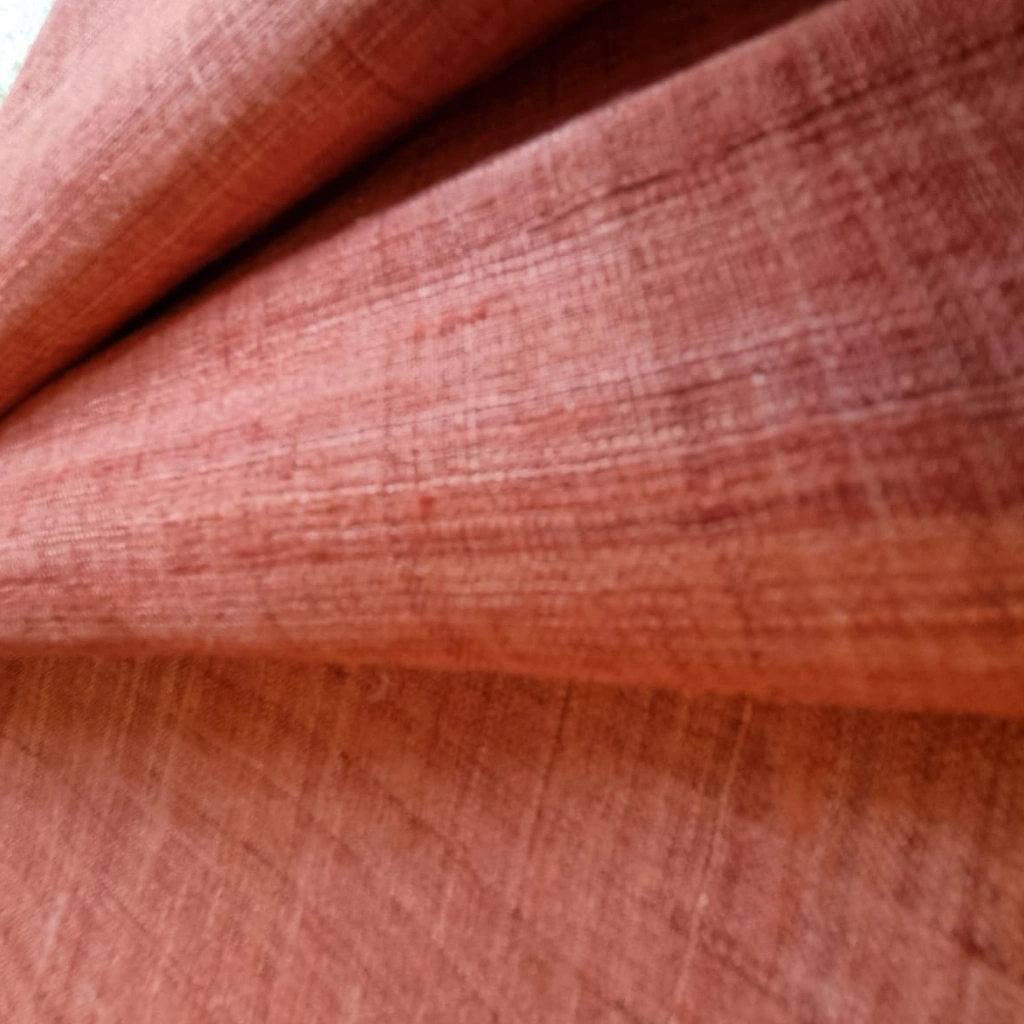 A close-up shot showing the rich, textured weave of terracotta-colored Eri silk fabric.