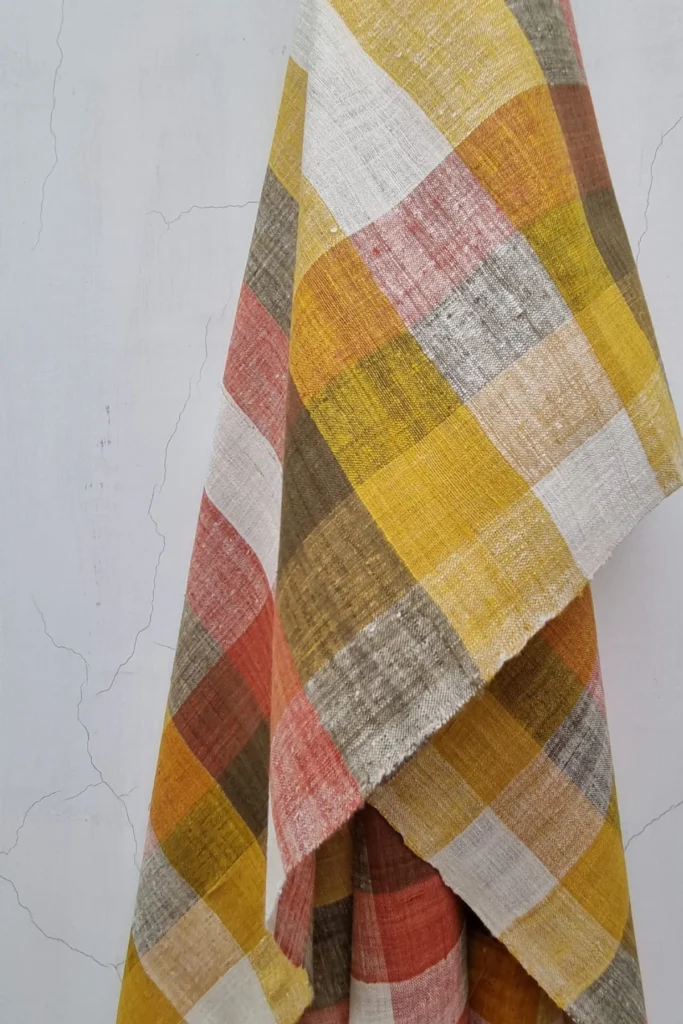 Close-up of artisan handwoven Ahimsa Eri silk stole with natural plant-dyed checks in yellow, olive, pink, and ivory tones.