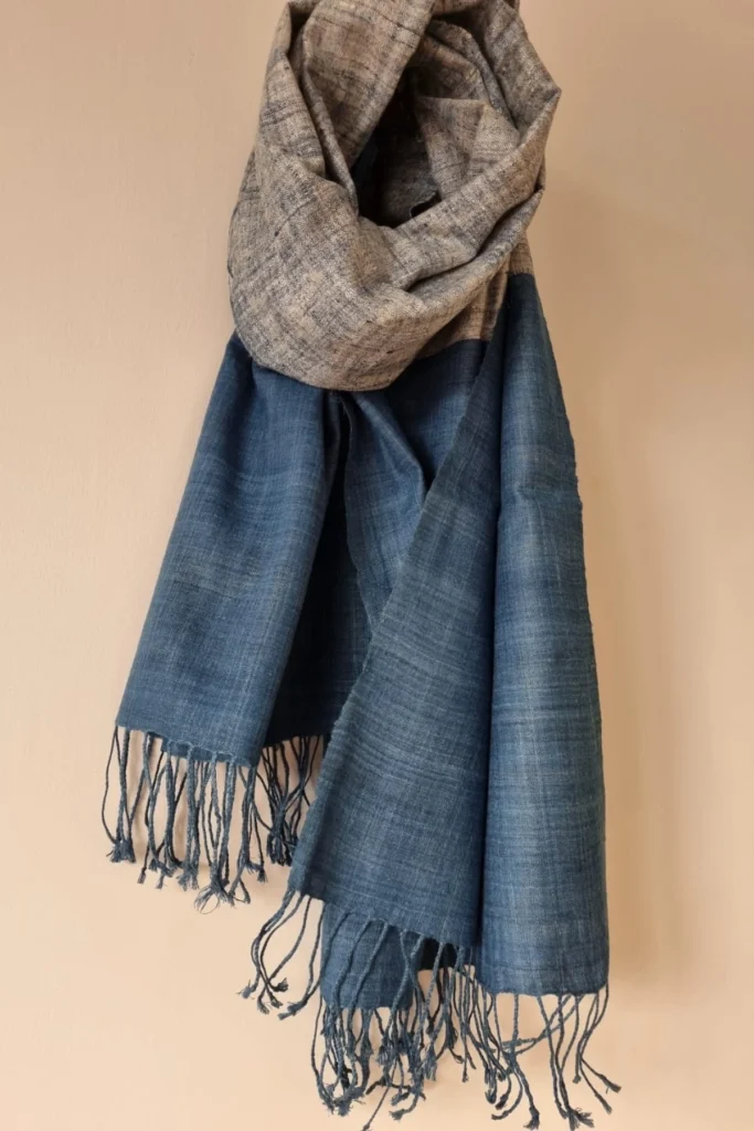 Handwoven Ahimsa Eri silk stole with indigo-dyed blue body and textured grey weave detail, finished with delicate fringes.