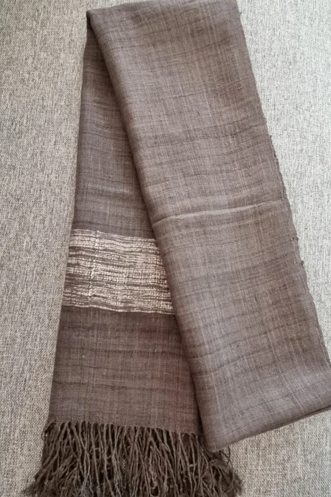 Handwoven natural grey Ahimsa Eri silk stole dyed with iron ore powder and Xilikha, featuring subtle woven detailing and soft fringes.