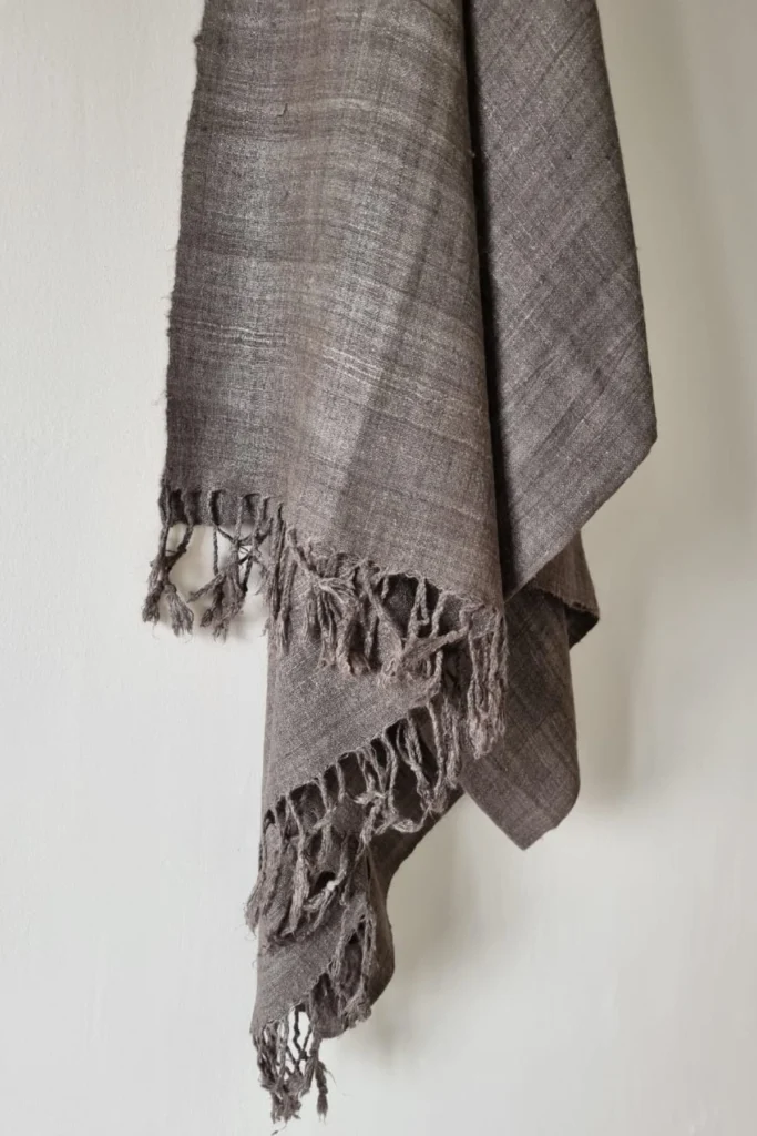 Handwoven Ahimsa Eri silk stole dyed with iron ore powder and myrobalan, featuring earthy charcoal-grey tones and artisanal fringes.